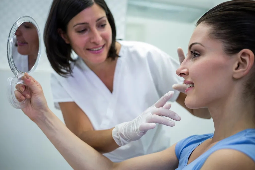 Clinician reviews nose shape with a patient using a mirror during a nose thread lift procedure consultation