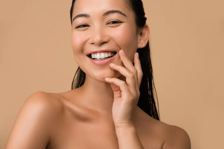 woman smiling with hands on jawline representing facial contouring treatment