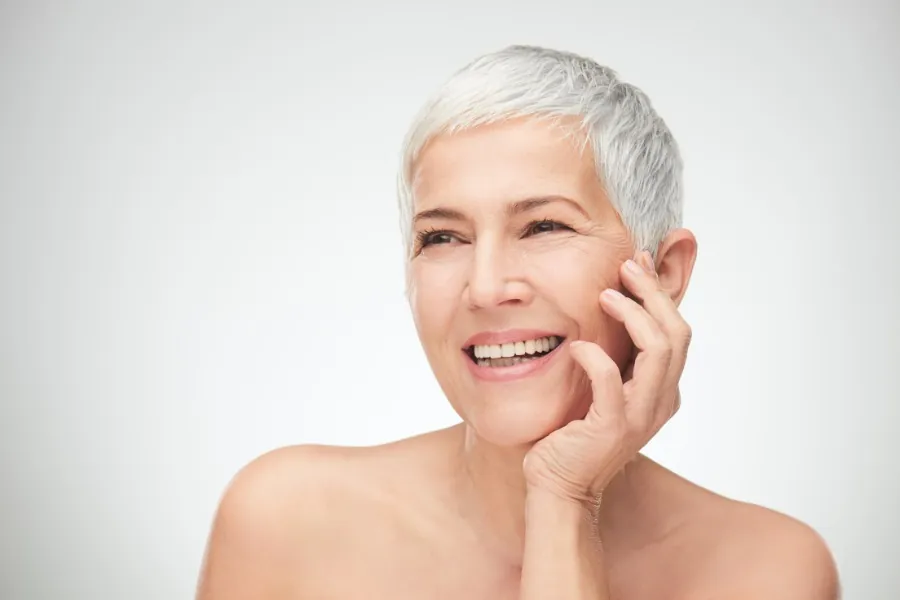 Woman with short grey hair smiling, showing natural facial balance and skin quality