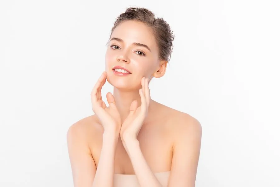A woman framing her face with her hands, demonstrating how facial contouring works to enhance natural bone structure and facial symmetry.