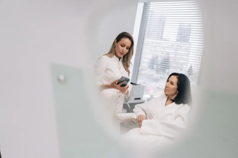 Clinician shows a treatment plan on her phone while reviewing the patient’s aesthetic maintenance schedule in clinic