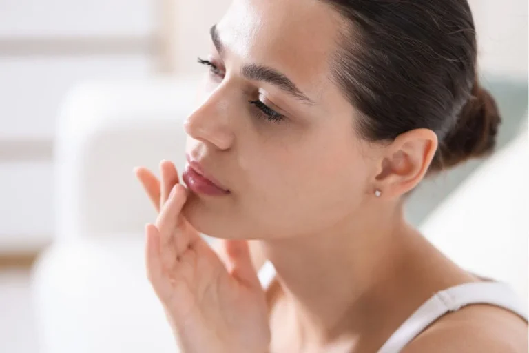 How to reduce swelling after lip treatment: A woman gently examines her lips during the recovery process.
