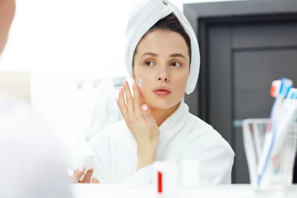 A woman applying a soothing cream to her face as part of a PicoSure treatment aftercare routine.