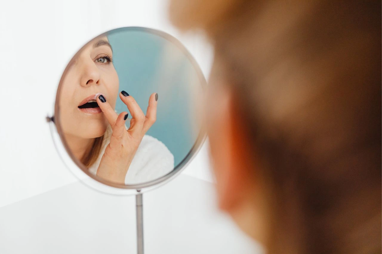 How long does it take for russian lips to heal: A woman examining her lips in a mirror during the initial recovery phase.