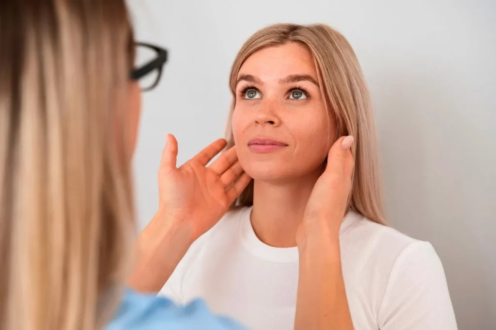 Practitioner examining a woman's jawline and cheeks during a facial thread lift consultation