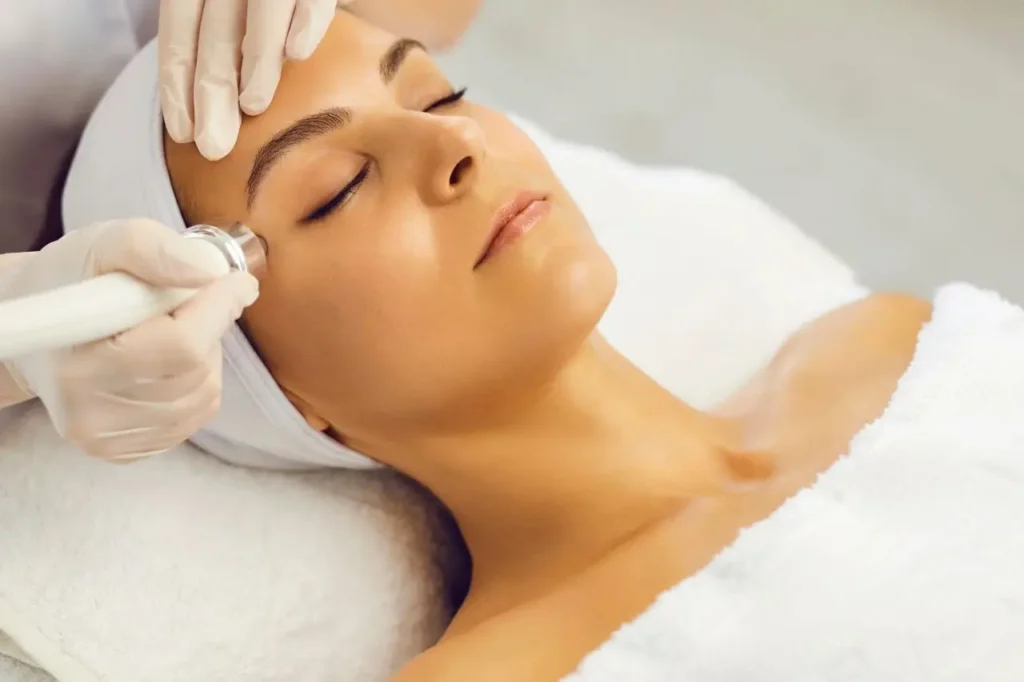 Woman receiving a Fotona Frac3 laser treatment to the cheek, gloved clinician holding the hand piece