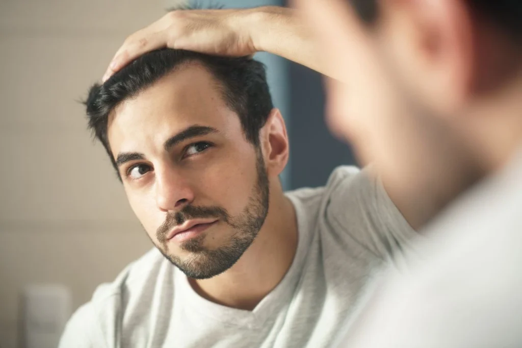 Man checking his hairline in the mirror while considering whether creatine causes hair loss in men