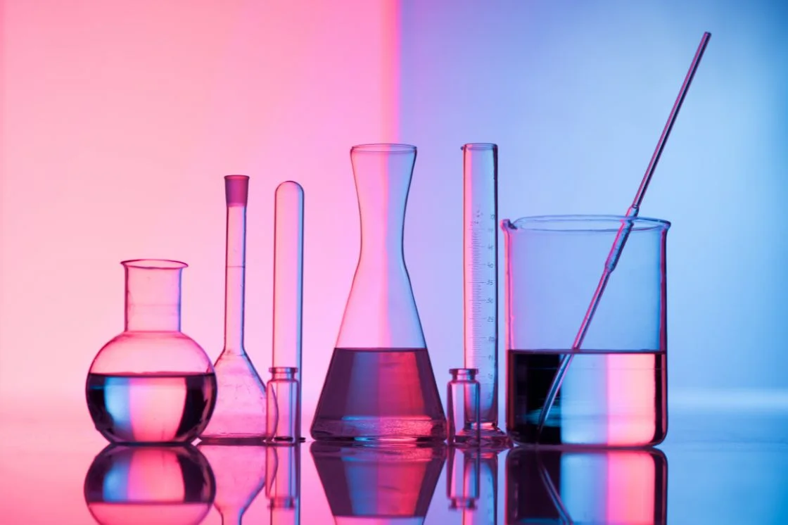 A row of laboratory glassware holding different solutions, illustrating the different types of chemical peels