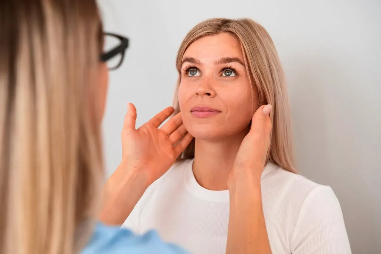 Practitioner examining a woman's jawline and cheeks during a facial thread lift consultation