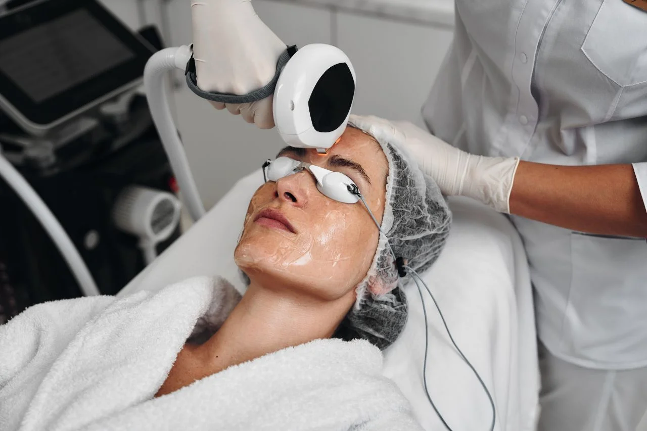 Woman receiving a Lumecca IPL treatment on her face from a practitioner in a clinic