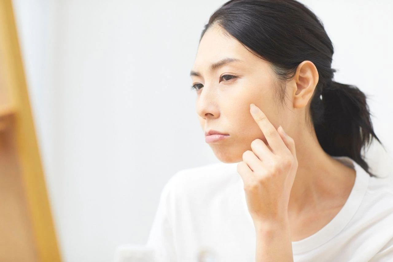 Woman assessing her facial skin quality before skin needling with exosomes treatment