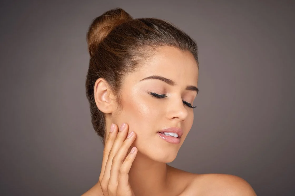 Woman with smooth, clear skin touching her face, illustrating what chemical peels can do for the skin